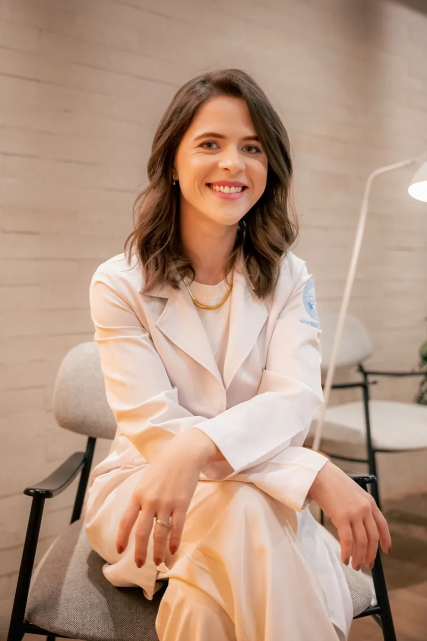 Dra. Rafaela Linhares sorrindo, de jaleco branco, em seu consultório